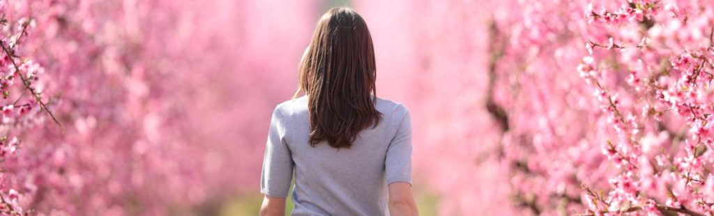 mujer andando por un campo de arboles floridos