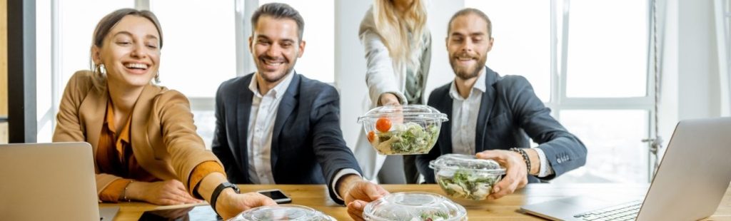 empleados sonrientes comiendo comida saludable