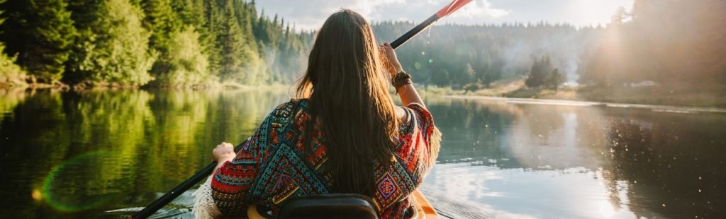 chica en canoa por un lago rodeado de árboles
