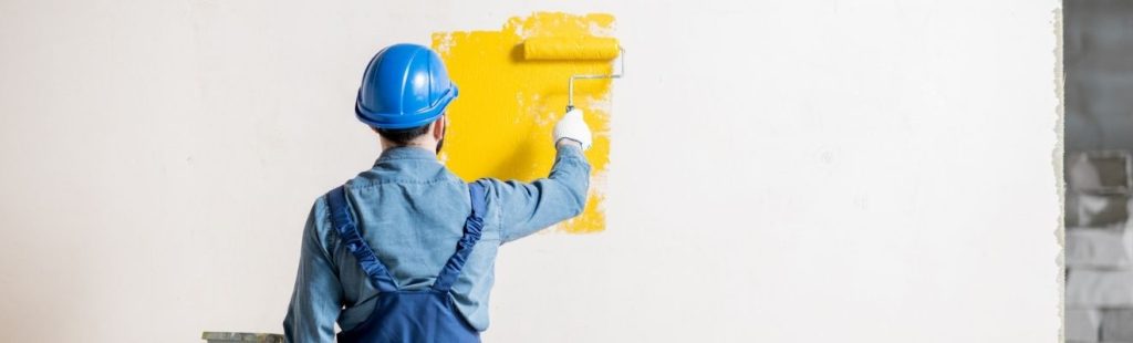 pintor con casco azul pintando una pared