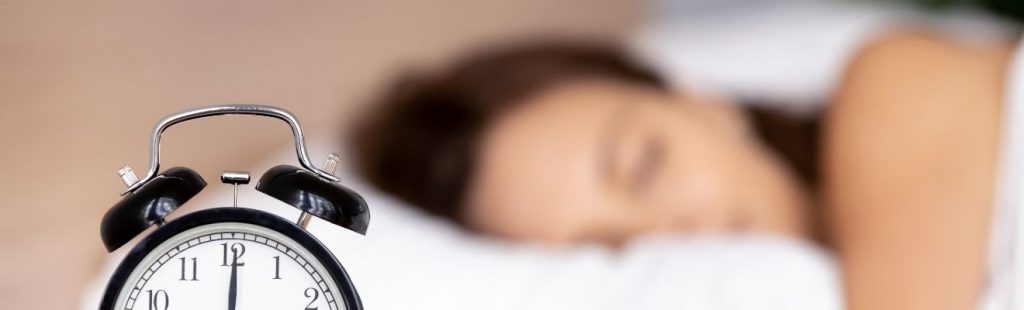 mujer durmiendo con reloj despertador en primer plano