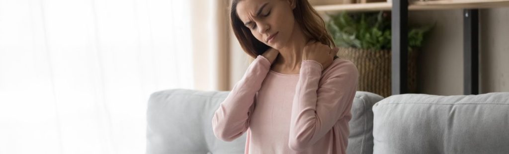 mujer sentada en el sofa con dolor de cuello