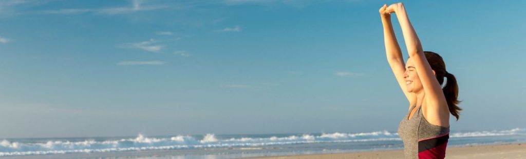 mujer estirándose en la playa