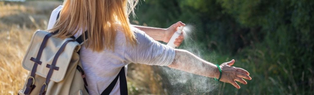 mujer echándose un anti mosquitos en el campo
