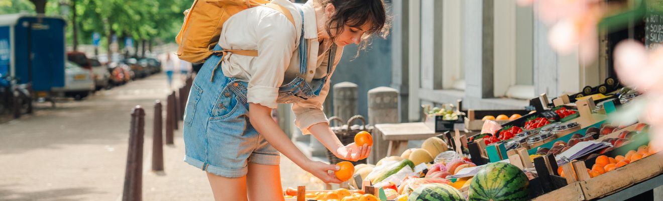 mujer seleccionando frutas en una tienda a pie de calle